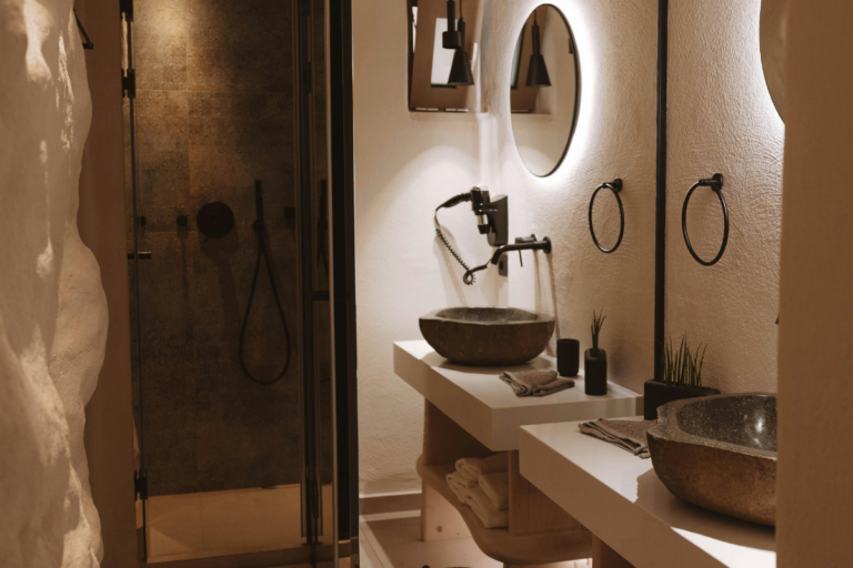 Modern comfortable travel accommodation bathroom with stone sink, mirror, and warm ambient lighting